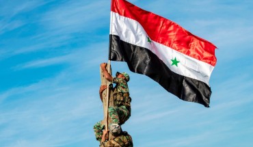 Syrian government soldiers climb up a wooden pole with a Syrian government national flag while deploying for the first time in the eastern countryside of the city of Qamishli in the northeastern Hasakah province on November 5, 2019.