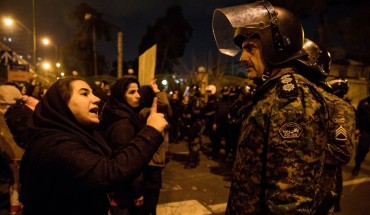 A woman attending a candlelight vigil, in memory of the victims of Ukraine International Airlines Boeing 737, talks to a policeman following the gathering in front of the Amirkabir University in the Iranian capital Tehran on January 11, 2020. 