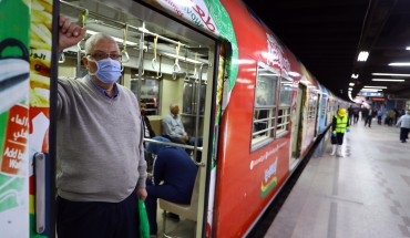 Man wearing a face mask stands in the doorway of public transportation