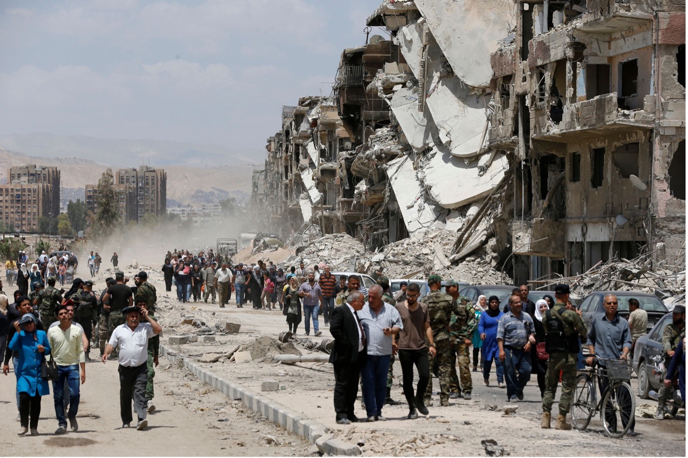 Image 2: Civilians and pro-government forces walk down Thalateen Street in Yarmouk refugee camp, southern Damascus, May 24, 2018. Photo by Louai Beshara/AFP via Getty Images