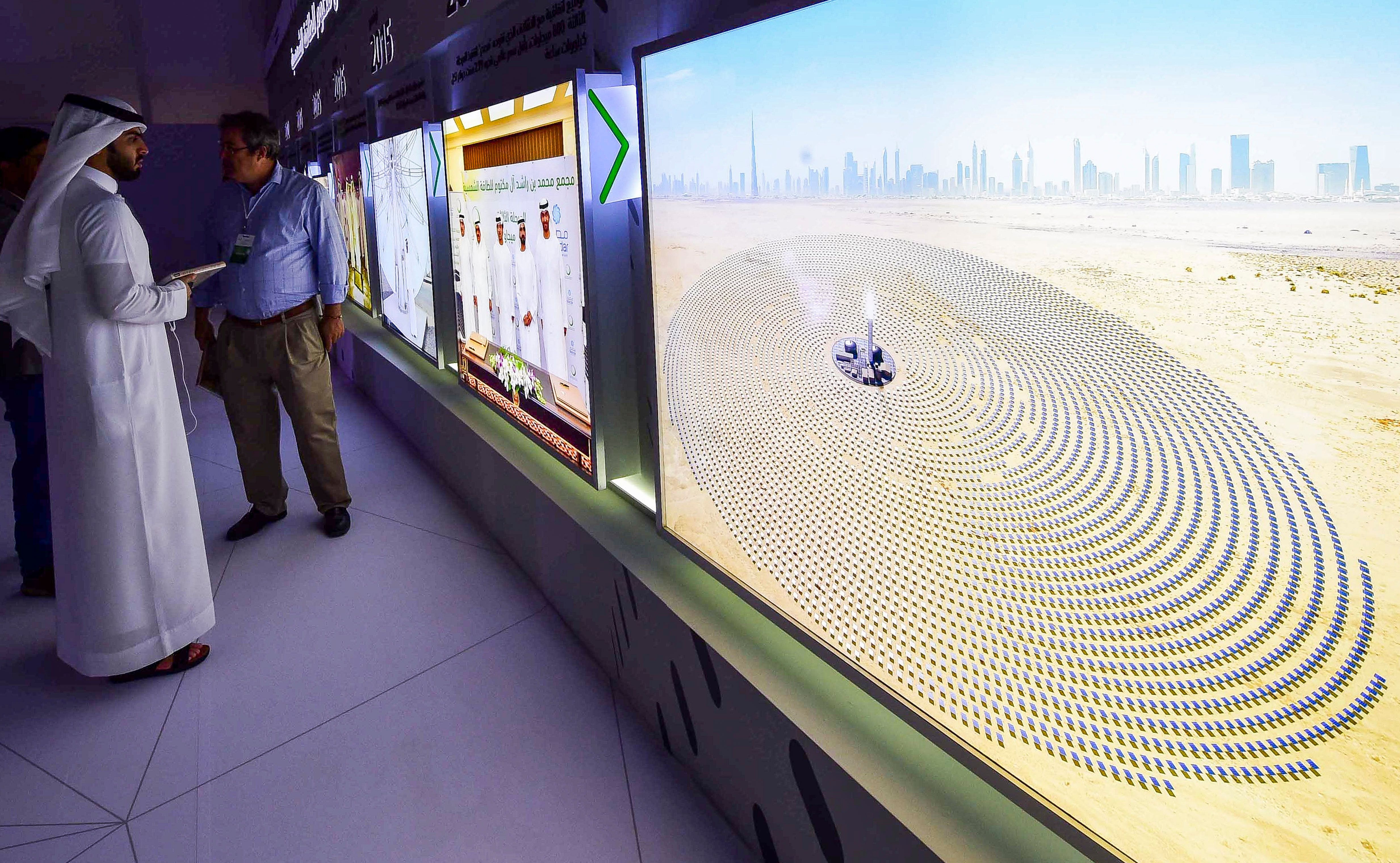 Visitors look at screens displaying images of the Mohammed bin Rashid Al Maktoum Solar Park on March 20, 2017, at the solar plant in Dubai. Photo by STRINGER/AFP via Getty Images.