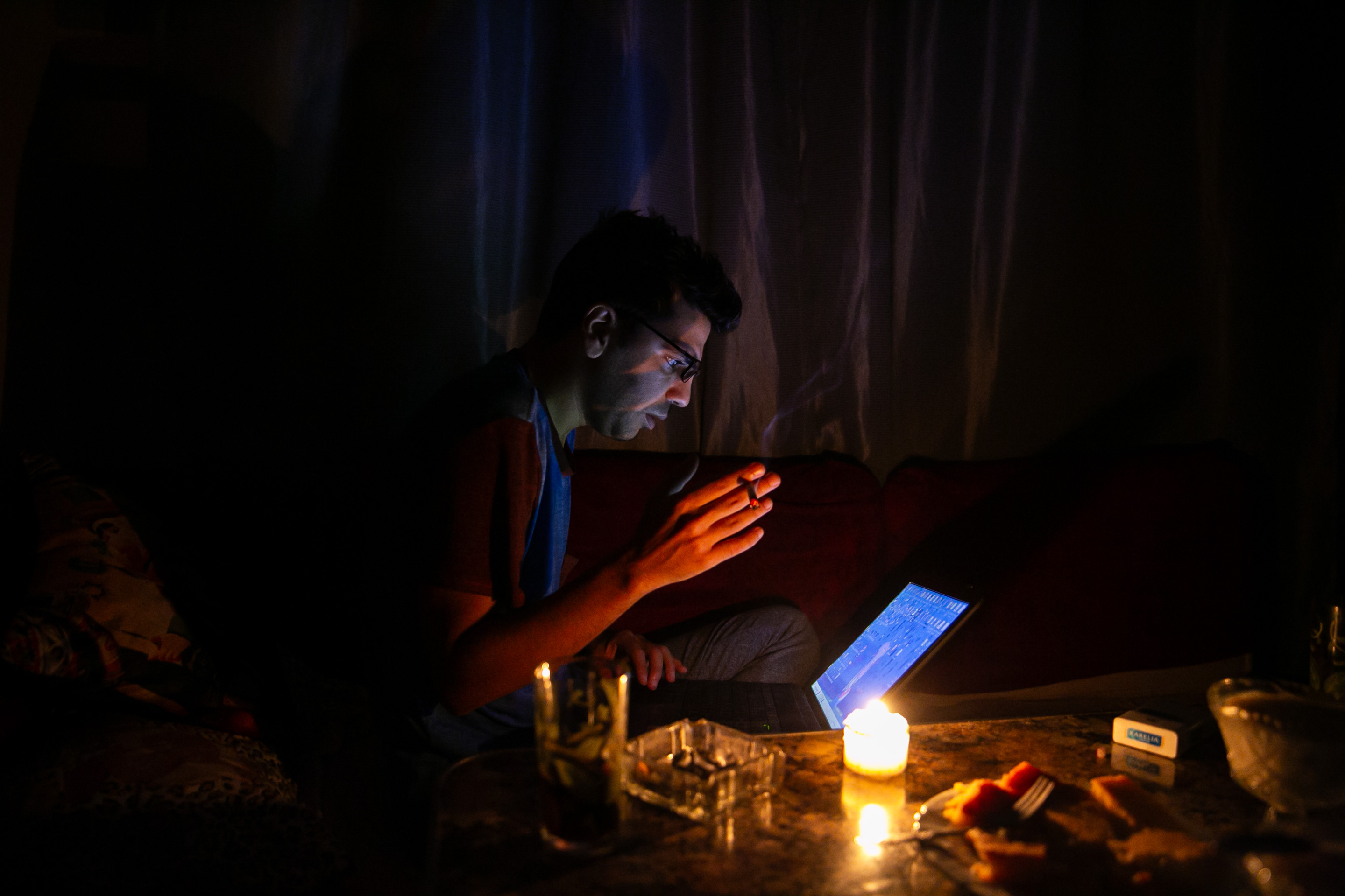  Egyptian using a laptop by candlelight during a blackout in 2023. Photo by Islam Safwat/Bloomberg via Getty Images.