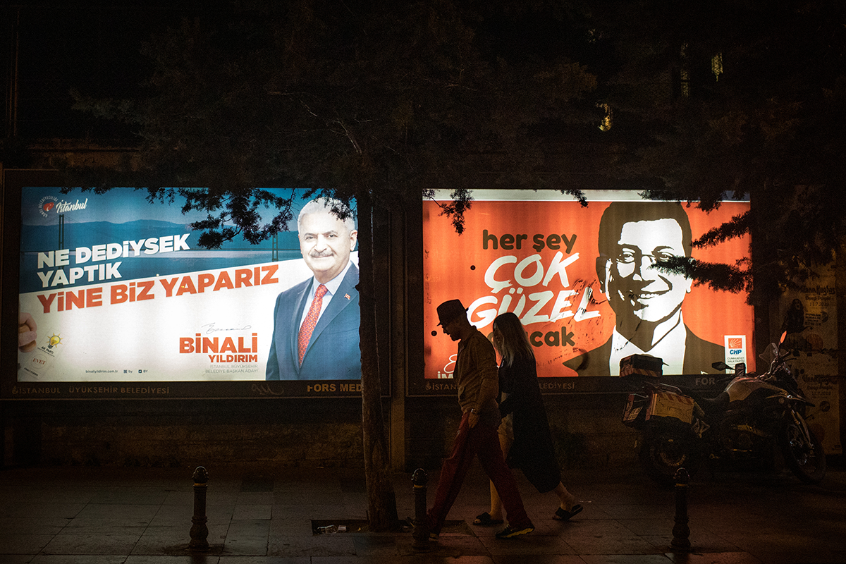 People walk past election posters of AKP candidate Binali Yıldırım (L) and CHP candidate Ekrem İmamoğlu (R) during campaigning in the re-run of the Istanbul mayoral election on June 01, 2019 in Istanbul. Photo by Chris McGrath/Getty Images.