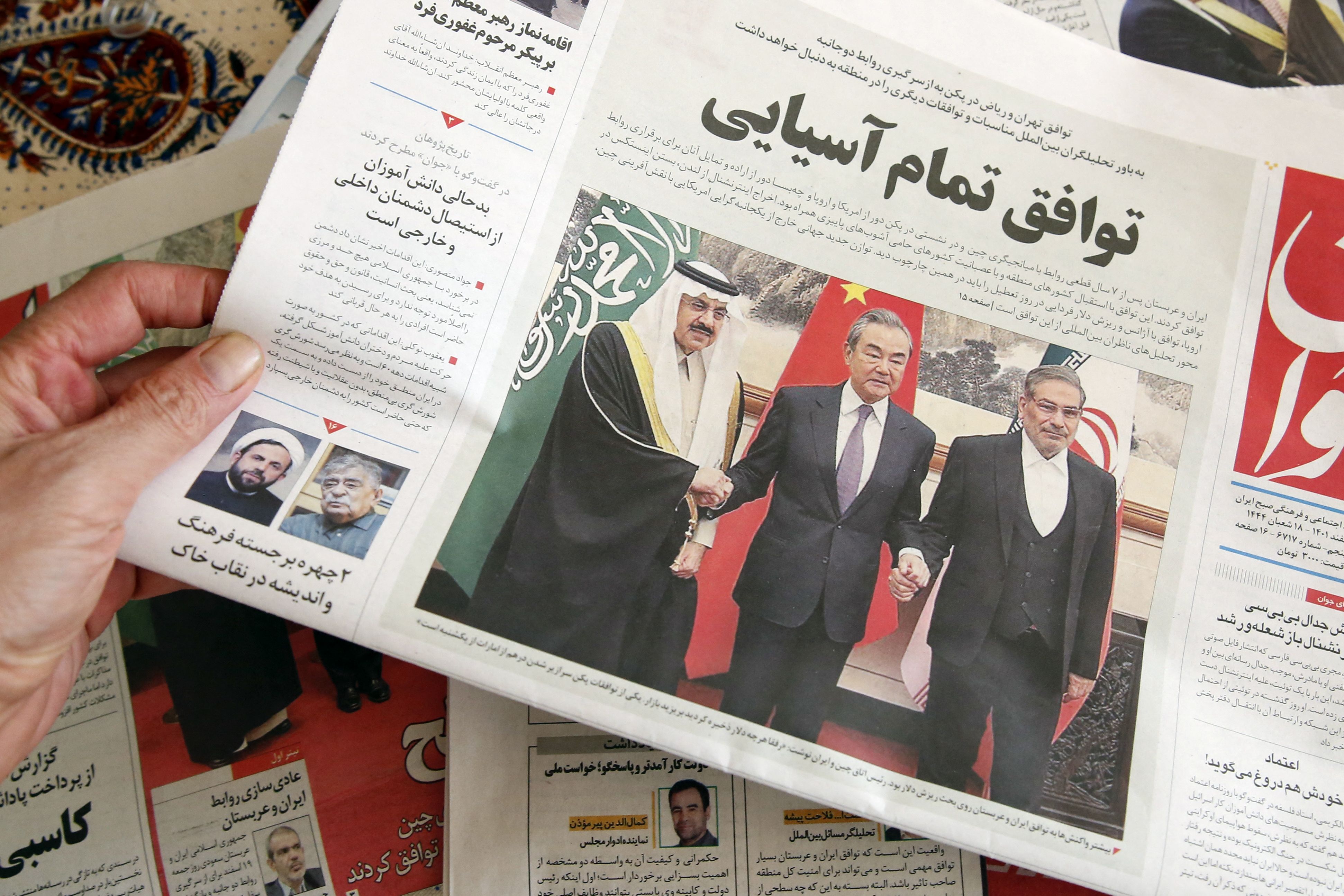 A man in Tehran holds a local newspaper reporting on the China-brokered deal between Iran and Saudi Arabia to restore ties on March, 11 2023. Photo by ATTA KENARE/AFP via Getty Images.