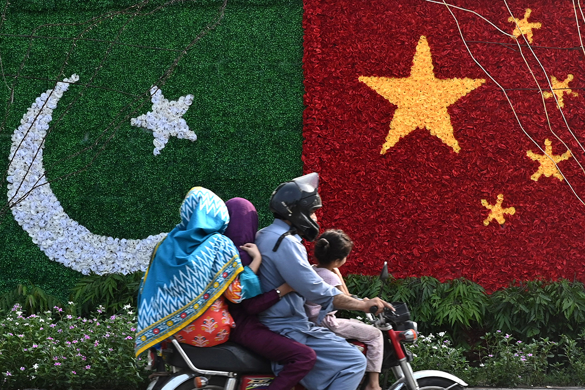 A family rides past a decoration in the shape of the national flags of China and Pakistan installed along a road ahead of the visit of Chinese Vice Premier He Lifeng, in Lahore on July 30, 2023. Photo by ARIF ALI/AFP via Getty Images.