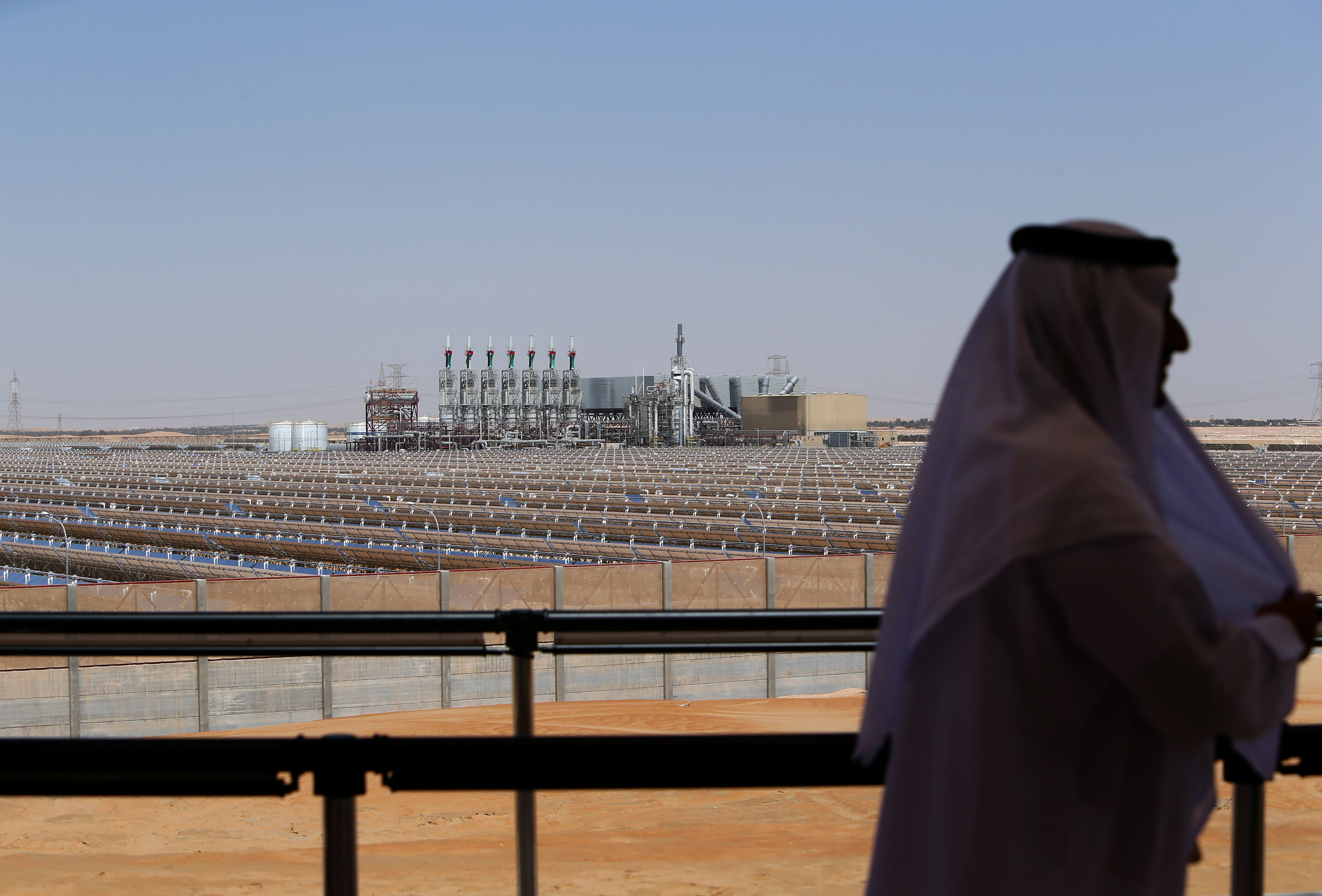 An Emirati man stands on a balcony overlooking the Shams 1 concentrated solar power plant in al-Gharibiyah district on the outskirts of Abu Dhabi during the facility’s inauguration in March 2013. Photo by MARWAN NAAMANI/AFP via Getty Images.