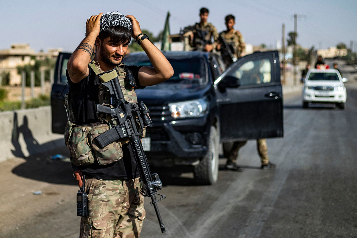 A fighter of the Syrian Democratic Forces (SDF) stands guard along a road as others deploy to impose a curfew in the town of al-Busayrah in Syria's northeastern Deir Ezzor province on September 4, 2023, during a guided media tour organised by the SDF. Days of deadly clashes between the US-backed, Kurdish-led Syrian Democratic Forces (SDF) and local fighters have rocked Deir Ezzor, threatening a fragile balance in the strategic area. (Photo by Delil SOULEIMAN / AFP) (Photo by DELIL SOULEIMAN/AFP via Getty Images)