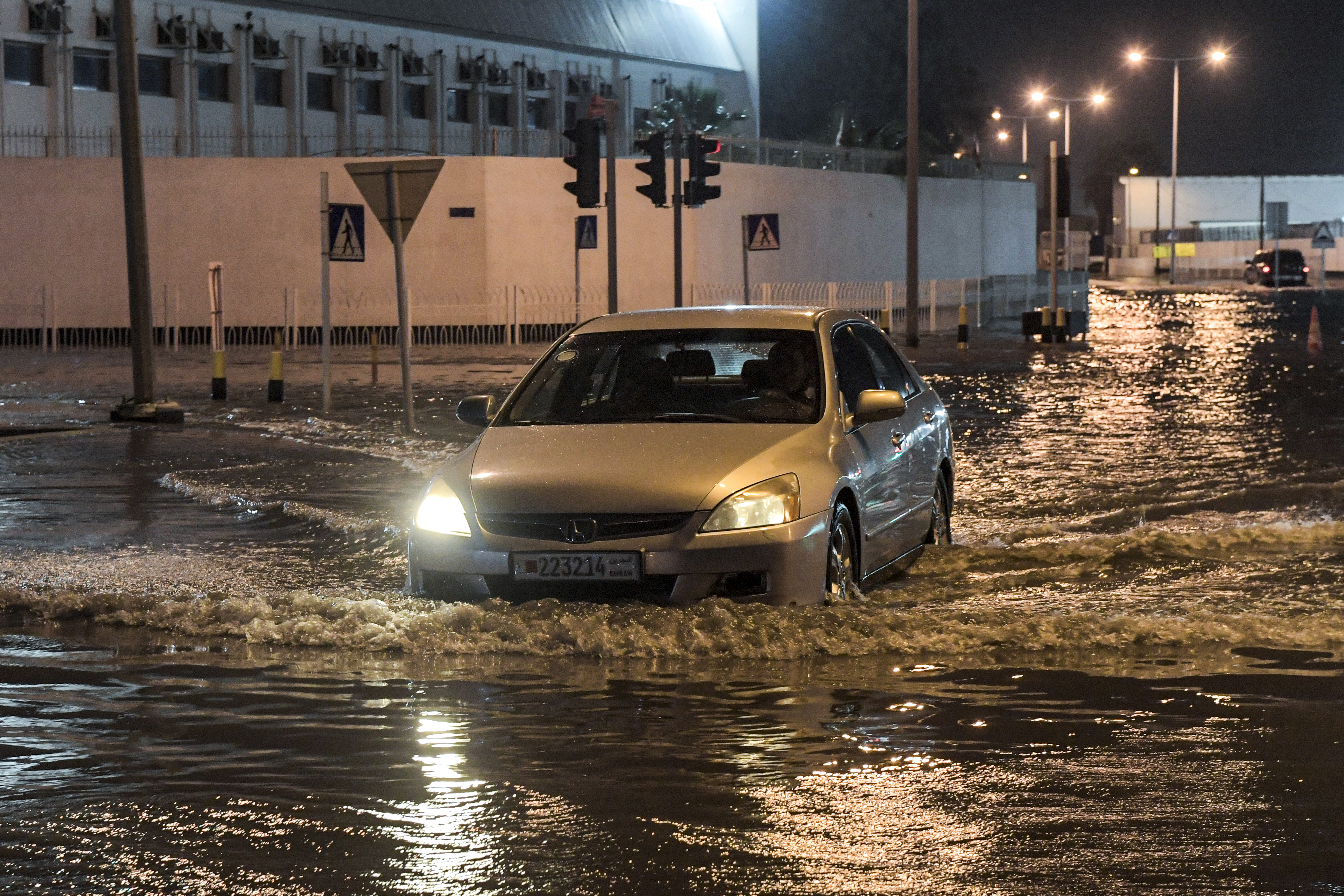 A vehicle moves along a flooded road in Bahrain’s Sitra island district during a heavy rain storm early on April 16, 2024. Photo by MAZEN MAHDI/AFP via Getty Images.