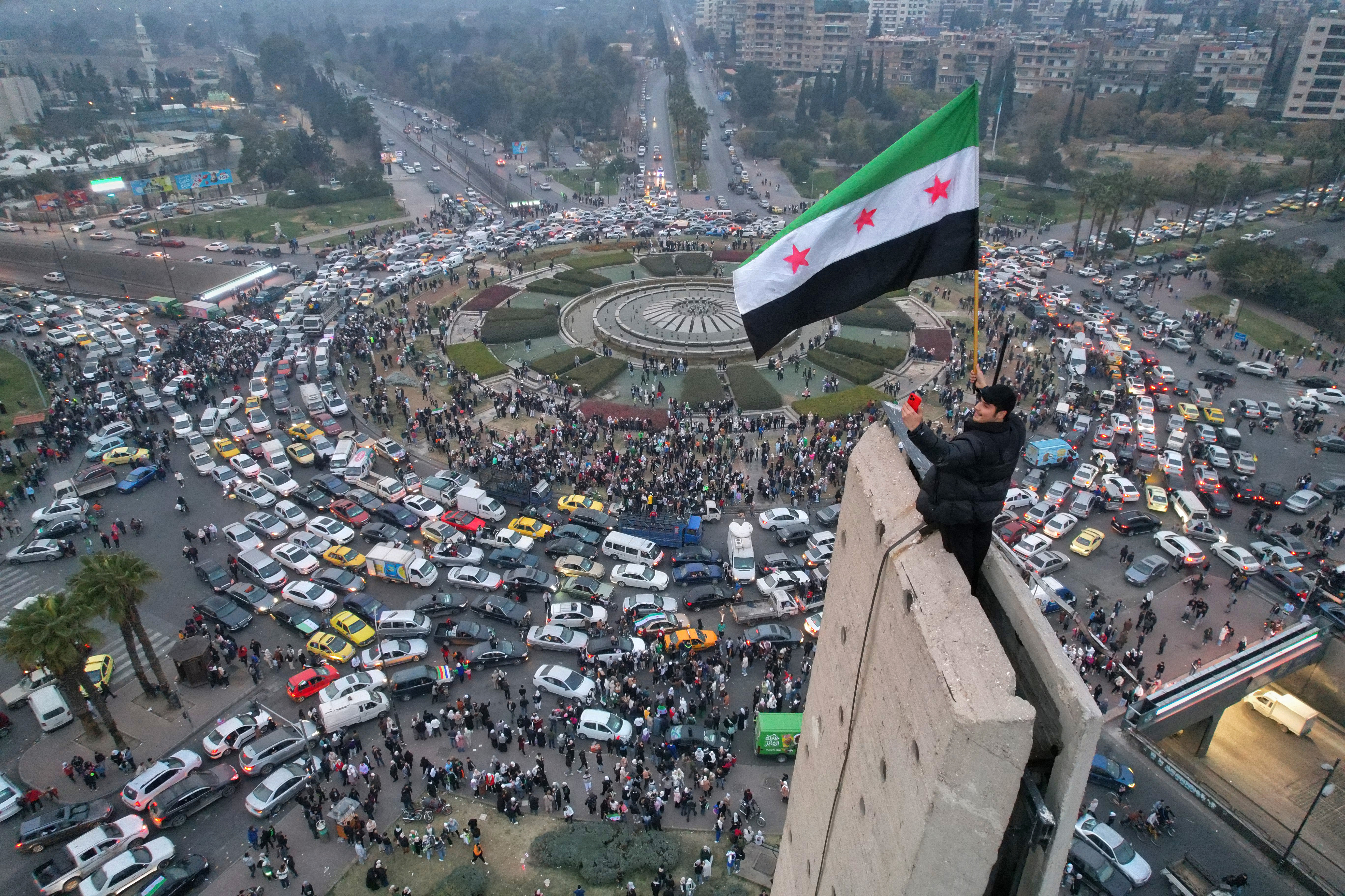 A Syrian man waving the independence-era Syrian flag over central Umayyad Square in Damascus on Dec. 11, 2024. Photo by Bakr Al-Kasem/AFP via Getty Images.