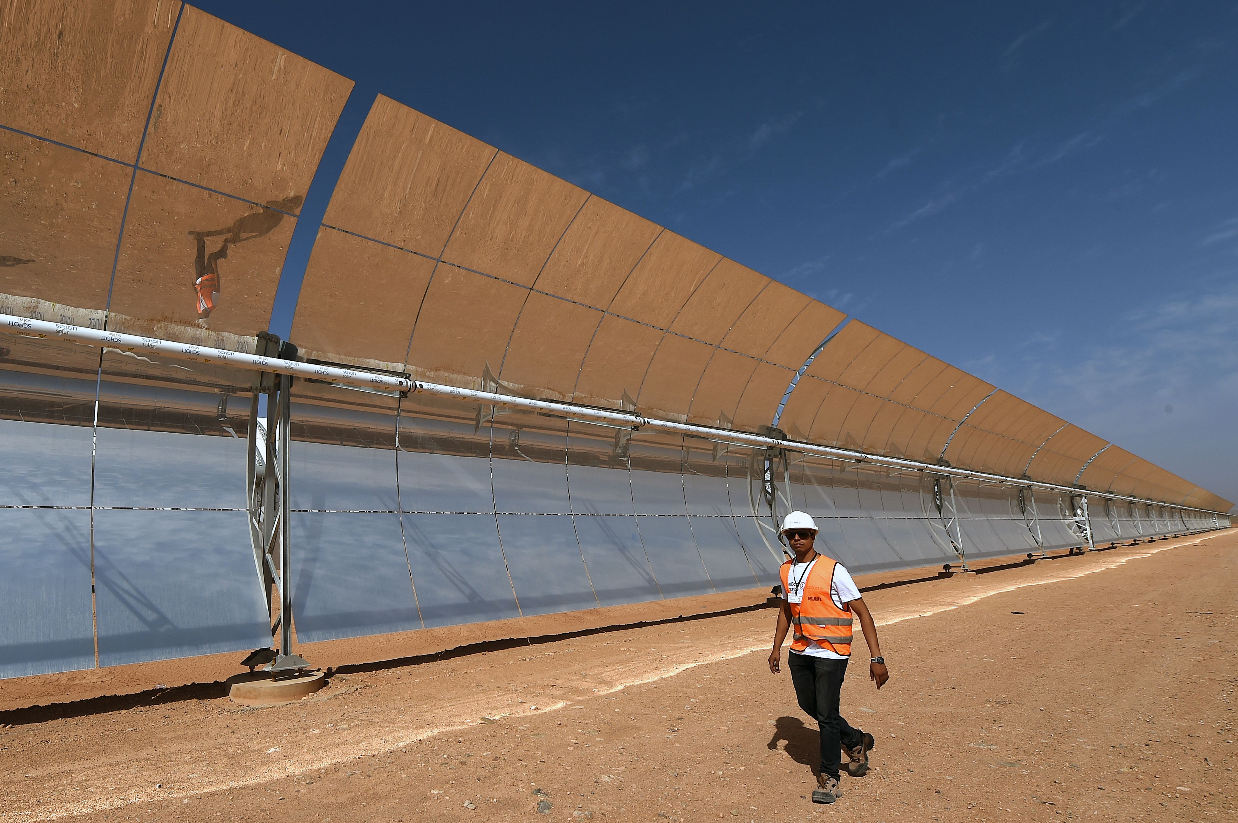 A Moroccan worker  alks in front of a solar array that is part of the Noor 1 solar power project in Ouarzazate on Oct. 19, 2014. Photo by FADEL SENNA/AFP via Getty Images.