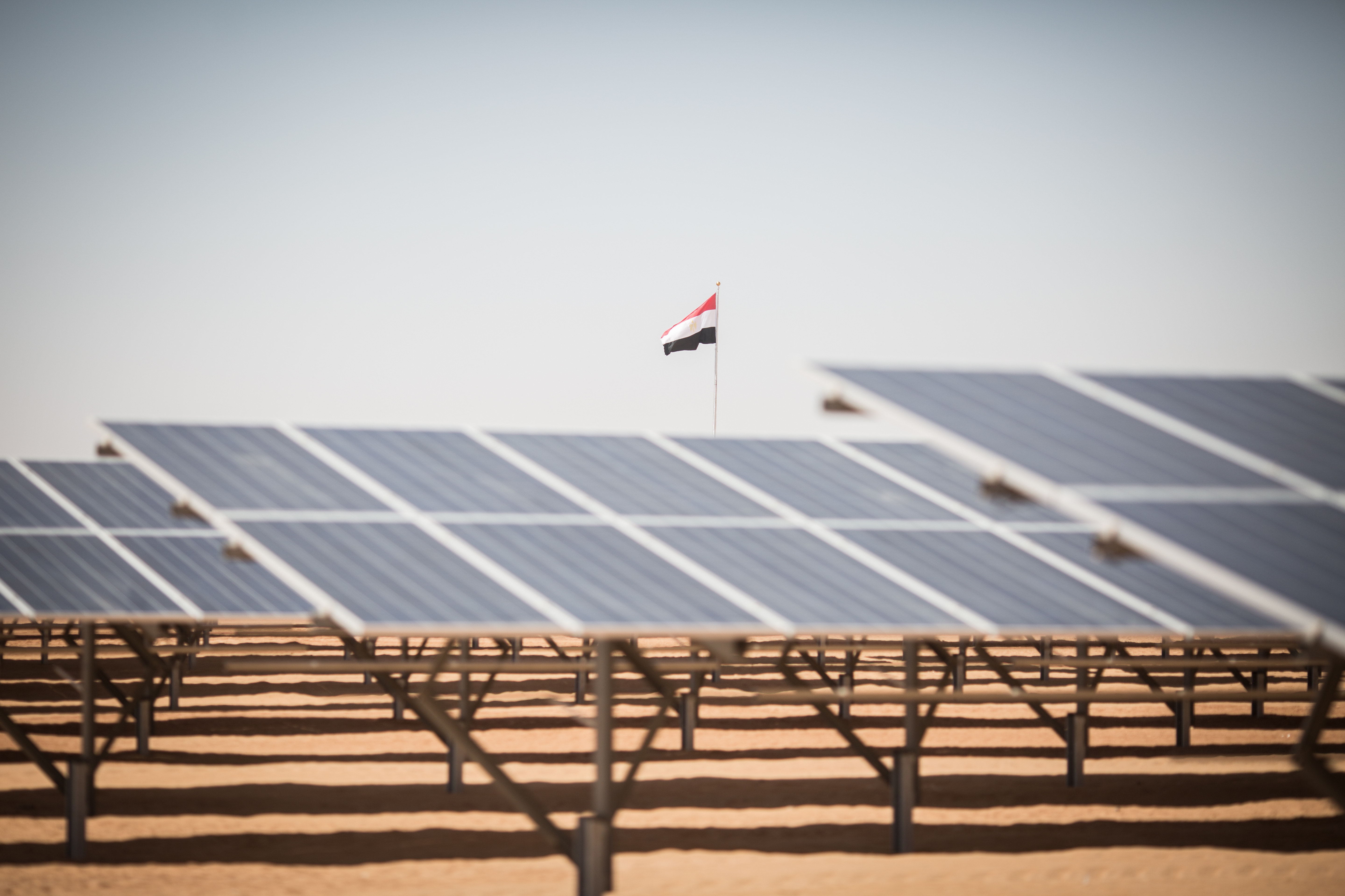 The Egyptian flag flies over solar panels during the inauguration ceremony for the first stage of the Infinity 50 Solar Park near Aswan, southern Egypt, on March 13, 2018. Photo by Oliver Weiken/picture alliance via Getty Images.