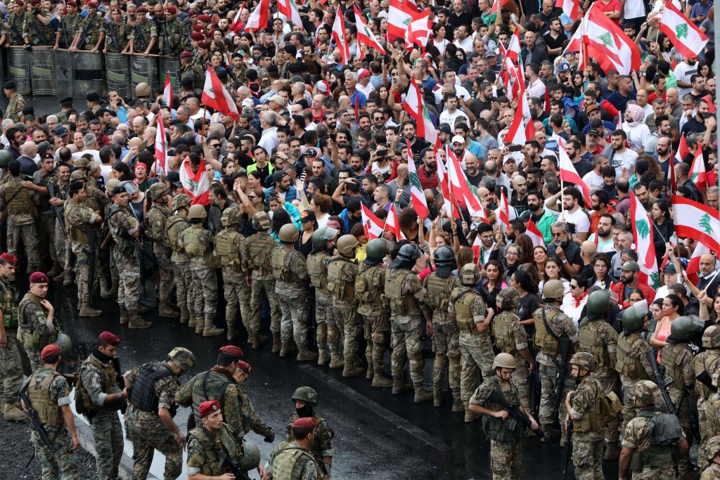 Anti-government protesters facing Lebanese army soldiers wave national flags in the area of Jal al-Dib in the northern outskirts of the Lebanese capital Beirut, on October 23, 2019.