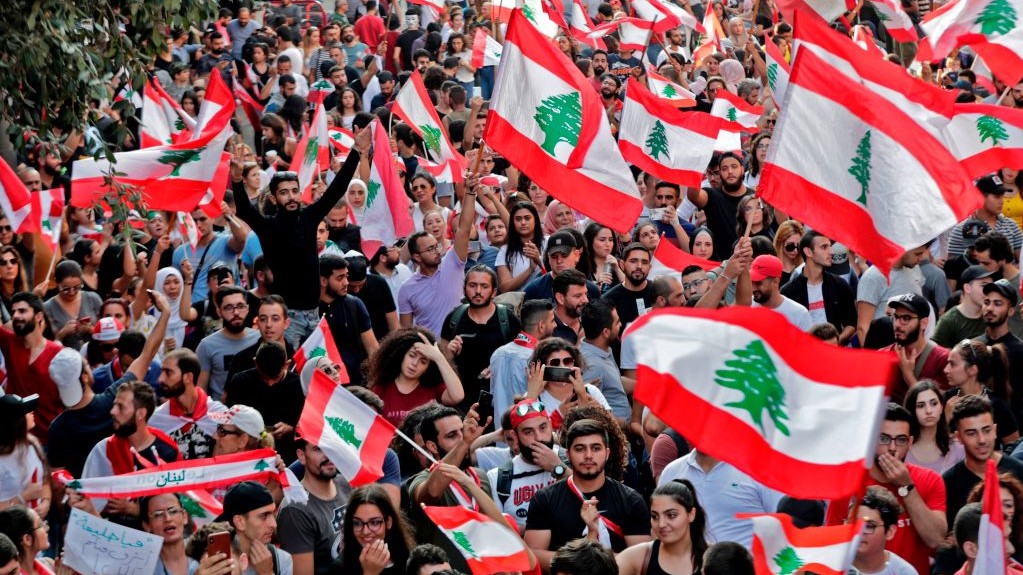 Lebanese protesters wave national flags during demonstrations to demand better living conditions and the ouster of a cast of politicians who have monopolised power and influence for decades, on October 21, 2019 in downtown Beirut. -