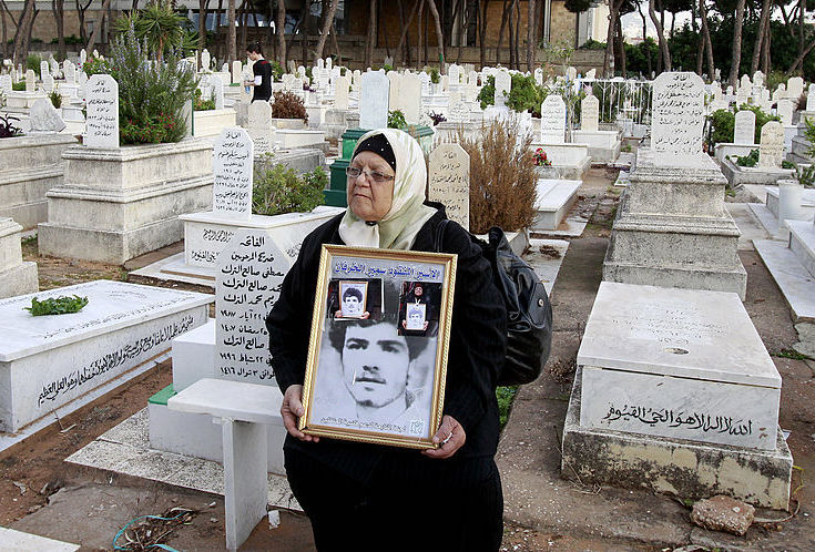 A Lebanese women holds an image of her missing son in a cemetery in the Beirut southern suburb of Qasqas on November 17, 2012 which is one of three neighbourhoods where the Lebanese state has recognised the presence of mass graves. (Photo by ANWAR AMRO/AFP via Getty Images)