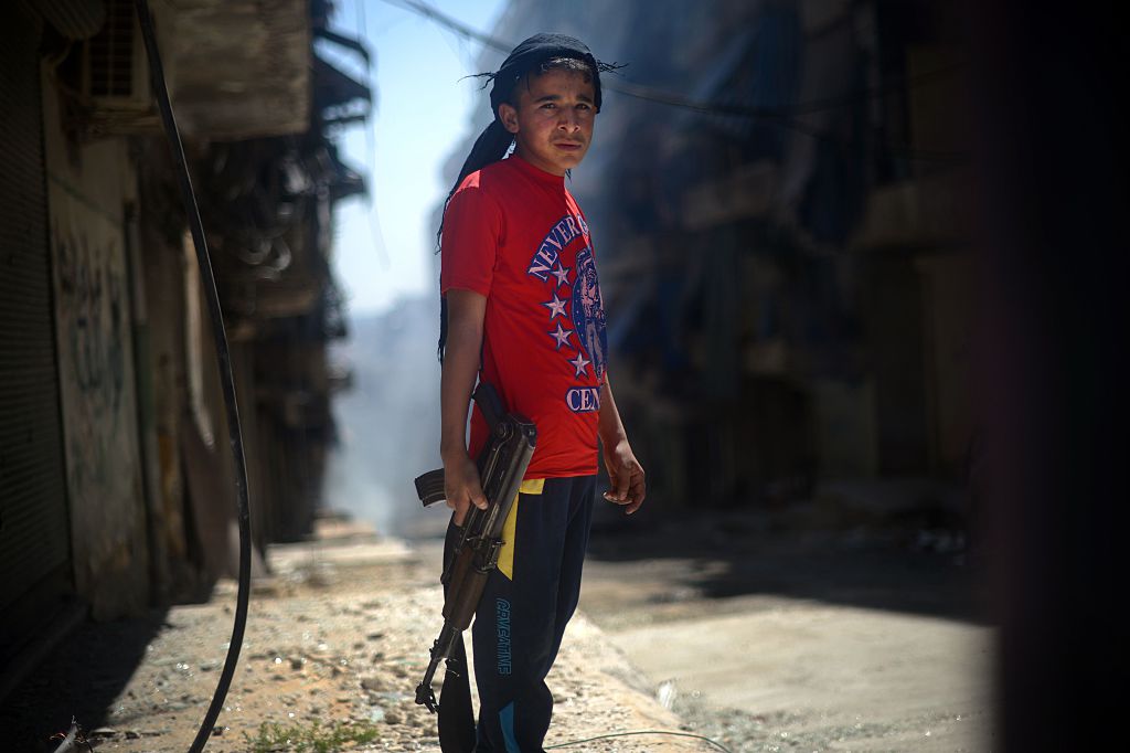 A Syrian boy holds an AK-47 assault rifle in the majority-Kurdish Sheikh Maqsud district of the northern Syrian city of Aleppo on April 14, 2013. (Photo by DIMITAR DILKOFF/AFP via Getty Images)