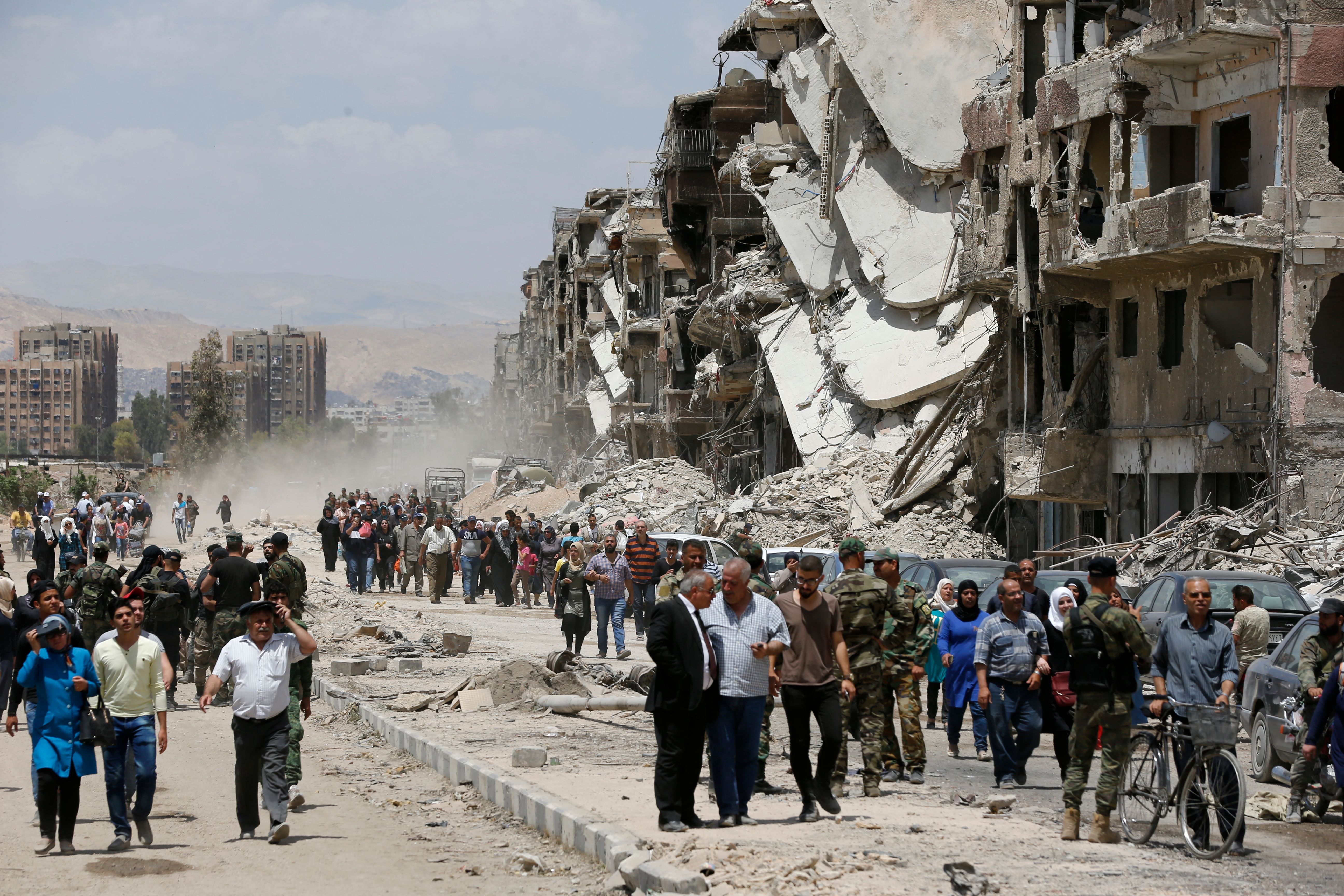 Photo above: Civilians and pro-government forces walk down the destroyed Thalateen Street in the Yarmouk Palestinian refugee camp on the southern outskirts of Damascus on May 24, 2018. Photo by Louai Beshara/AFP via Getty Images.