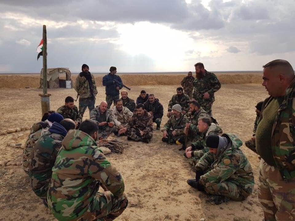 Latakia National Defense Forces (NDF) fighters gather around their commander at an outpost outside Palmyra.