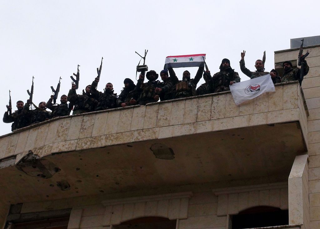 Forces loyal to the Syrian regime celebrate with national flags after Syria's army and allied forces took full control from rebel groups of the strategic town of Salma. Photo credit: STRINGER/AFP/Getty Images.