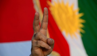  A demonstrator makes the "victory" sign standing in front of a Kurdish flag. 