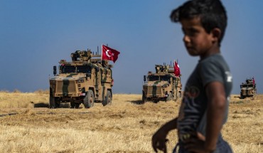 A Syrian boy watches as Turkish military vehicles, part of a US military convoy, take part in joint patrol in the Syrian village of al-Hashisha on the outskirts of Tal Abyad town along the border with Turkey, on October 4, 2019. 