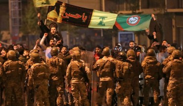 Supporters of Lebanese Shiite groups Hezbollah and Amal wave flags and chant in front of army soldiers in the capital Beirut, on November 25, 2019.