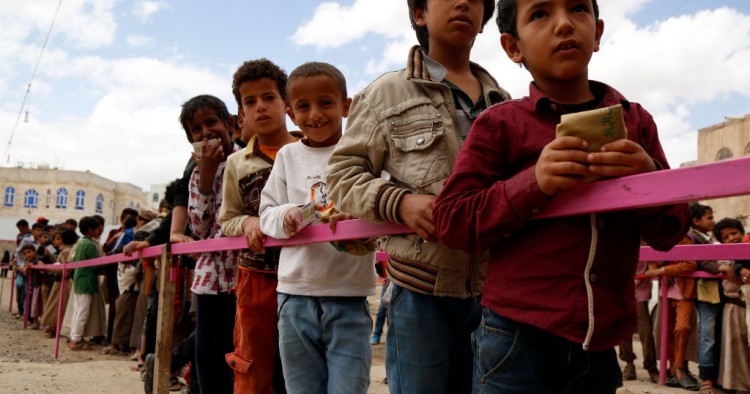 Yemeni children queue to obtain dinner meal distributed as aids by a local charity, the Amalona organization, on May 18, 2019 in Sana’a, Yemen. 
