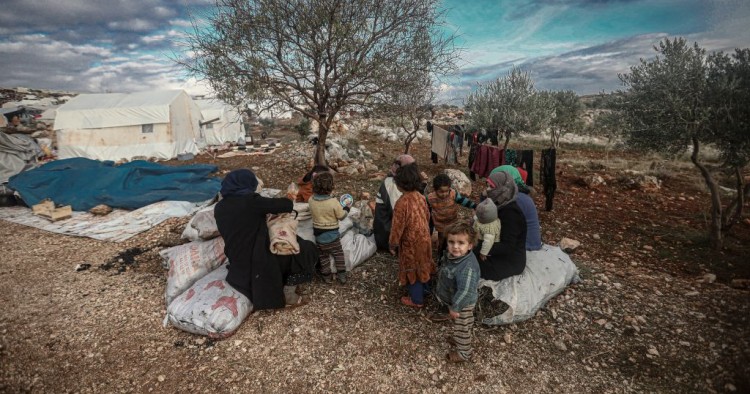 Syrian families, who have been forced to displace despite attacks carried out by Assad regime and Russia, sit on soil field despite the cold weather during winter season at Harbanush village in Idlib, Syria on December 28, 2019. 