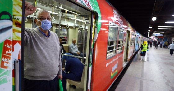 Man wearing a face mask stands in the doorway of public transportation