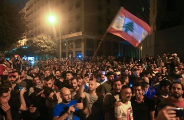 Demonstrators wave a flag during a protest against a government decision to tax calls made on messaging applications on October 17, 2019 outside the government palace in Beirut. 