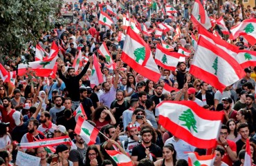 Lebanese protesters wave national flags during demonstrations to demand better living conditions and the ouster of a cast of politicians who have monopolised power and influence for decades, on October 21, 2019 in downtown Beirut. 