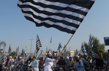 An activists of the Jamiat Ulema-e-Islam waves the party flag during the anti-government "Azadi March" towards Islamabad, in Peshawar on October 27, 2019.