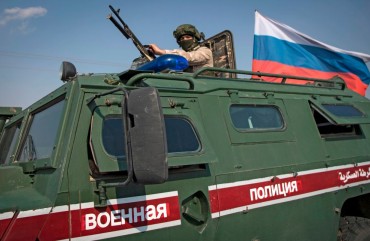 A soldier rides atop a Russian military vehicle near the Syrian northeastern city of Qamishli on October 26, 2019. 