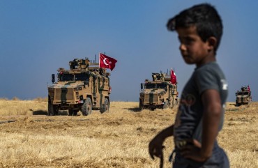A Syrian boy watches as Turkish military vehicles, part of a US military convoy, take part in joint patrol in the Syrian village of al-Hashisha on the outskirts of Tal Abyad town along the border with Turkey, on October 4, 2019. 