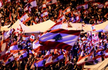Lebanese anti-government protesters wave national flags as they take part in an anti-govenment demonstration in the capital Beirut's downtown district on November 3, 2019. 