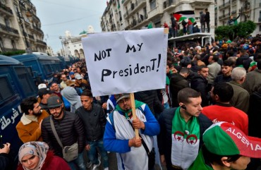 An Algerian protester lifts a placard in the capital Algiers on December 13, 2019, as he takes part in a demonstration to reject the results of the presidential elections. 