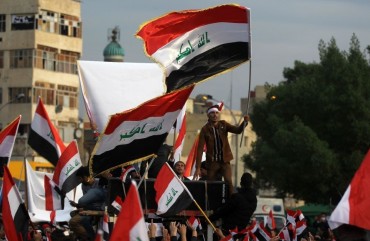 Iraqi demonstrators wave national flags as they take part in an anti-government demonstration in the capital Baghdad's Tahrir Square, on December 6, 2019. 