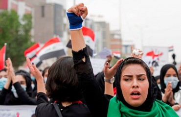 An Iraqi woman raises her fist as she takes part in an anti-government march in the center of the southern city of Basra on December 2, 2019.