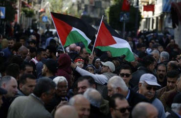 Palestinians wave national flags as they march in the streets of the occupied West Bank city of Ramallah, calling for the cessation of divisions between Fatah and Hamas and the unification of the West Bank and Gaza Strip, on January 12, 2019. 