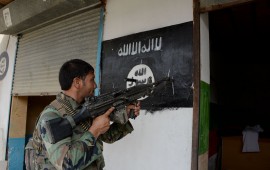 An Afghan soldier points his gun at an ISIS banner as he patrols in Nangarhar Province 