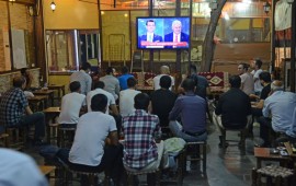 People watch a live broadcast of a televised debate between Istanbul's mayoral candidate Binali Yildirim (R) of Turkey's ruling AKP, and Istanbul's deposed mayor Ekrem Imamoglu (L) of the CHP, is shown on a screen at a tea house in Diyarbakir on June 16, 2019.