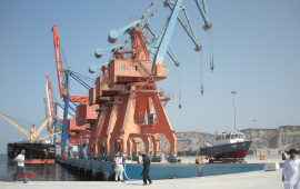 In this photograph taken on October 4, 2017, Pakistani labourers walk through Gwadar port. Remote and impoverished, Pakistan's Gwadar port at first glance seems an unlikely crown jewel in a multi-billion dollar development project with China aimed at constructing a 21st century Silk Road. Situated on a barren peninsula in the Arabian Sea, Gwadar, or the "gate of the wind", owes its fortuitous selection as Pakistan's next economic hub to its strategic location near the Strait of Hormuz. 