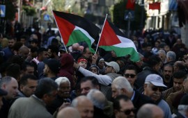 Palestinians wave national flags as they march in the streets of the occupied West Bank city of Ramallah, calling for the cessation of divisions between Fatah and Hamas and the unification of the West Bank and Gaza Strip, on January 12, 2019.