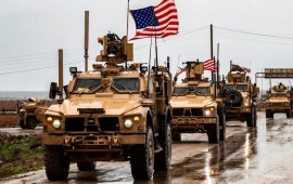 A row of U.S. troops with flags waving in Syria.