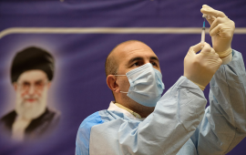 An Iranian medical personnel fills a syringe with the Russian Sputnik-V vaccine, The first registered vaccine against COVID-19, while standing next to a portrait of Irans Supreme Leader Ayatollah Ali Khamenei during a ceremony of initiation of general vaccination against the new coronavirus disease, in a hospital in western Tehran on February 9, 2021. (Photo by Morteza Nikoubazl/NurPhoto via Getty Images)