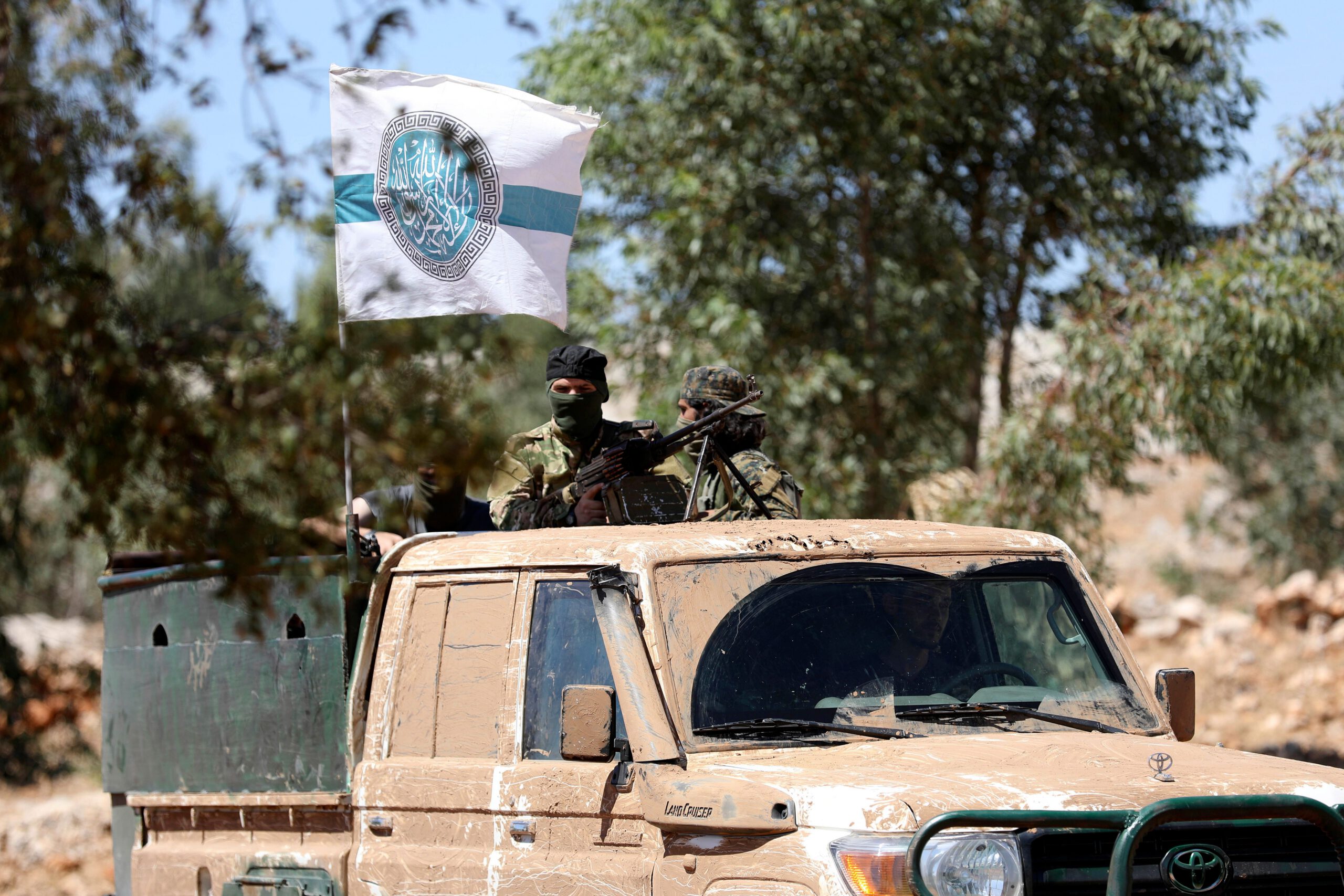 Syrian fighters stand at the back of a pick-up as they attend a mock battle in anticipation of an attack by the regime on Idlib province and the surrounding countryside, during a graduation of new Hayat Tahrir al-Sham (HTS) members at a camp in the countryside of the northern Idlib province.