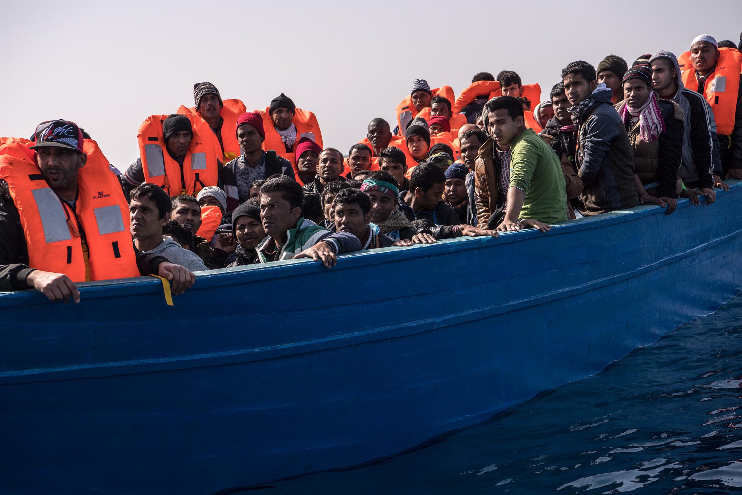 Migrants and refugees are assisted by members of the Spanish NGO Proactiva Open Arms as they crowd on board of a wooden boat sailing out of control at 20 miles (38 km) north of Sabratha, Libya on February 18, 2017.