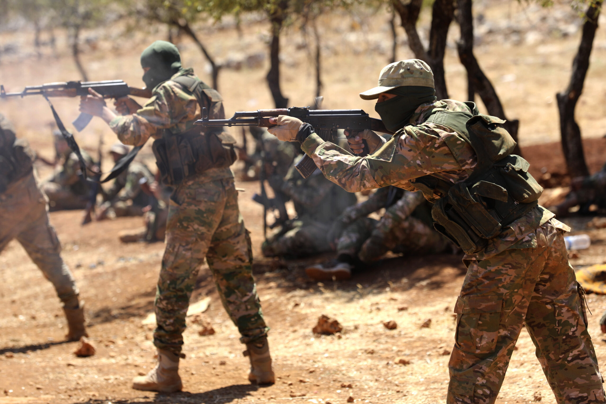 Syrian fighters fire AK-47 at a mock battle during a graduation of new Hayat Tahrir al-Sham (HTS) members