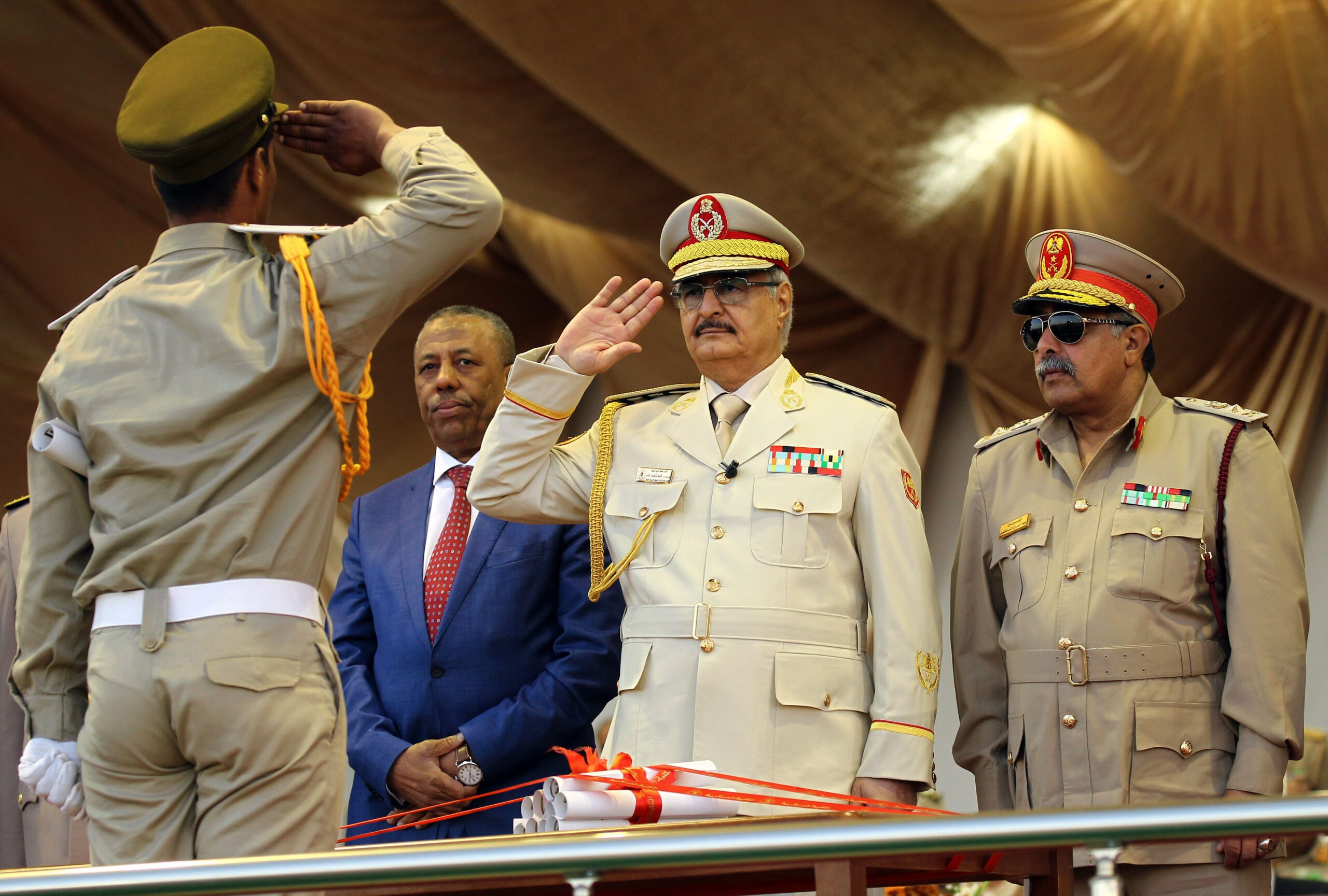 Libyan Strongman Khalifa Haftar salutes next to Libyan National Army's Chief Of Staff Abdelrazak al-Nadhuri and Libyan former prime minister Abdullah al-Thani.