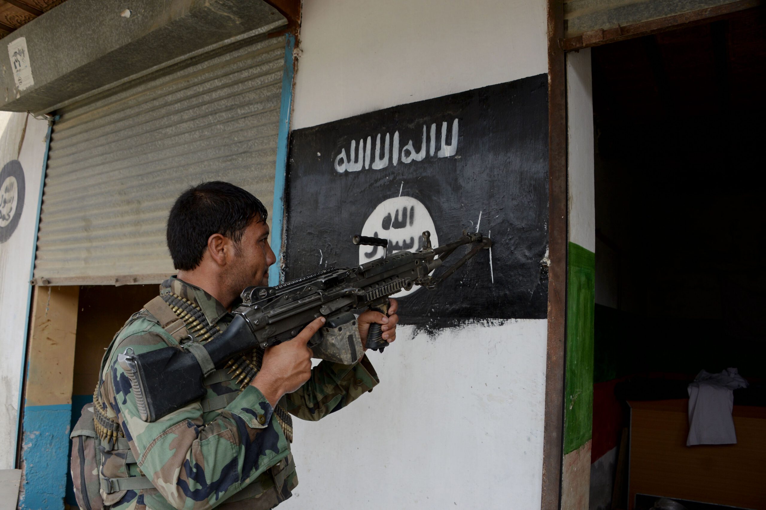 An Afghan soldier points his gun at an ISIS banner as he patrols in Nangarhar Province 