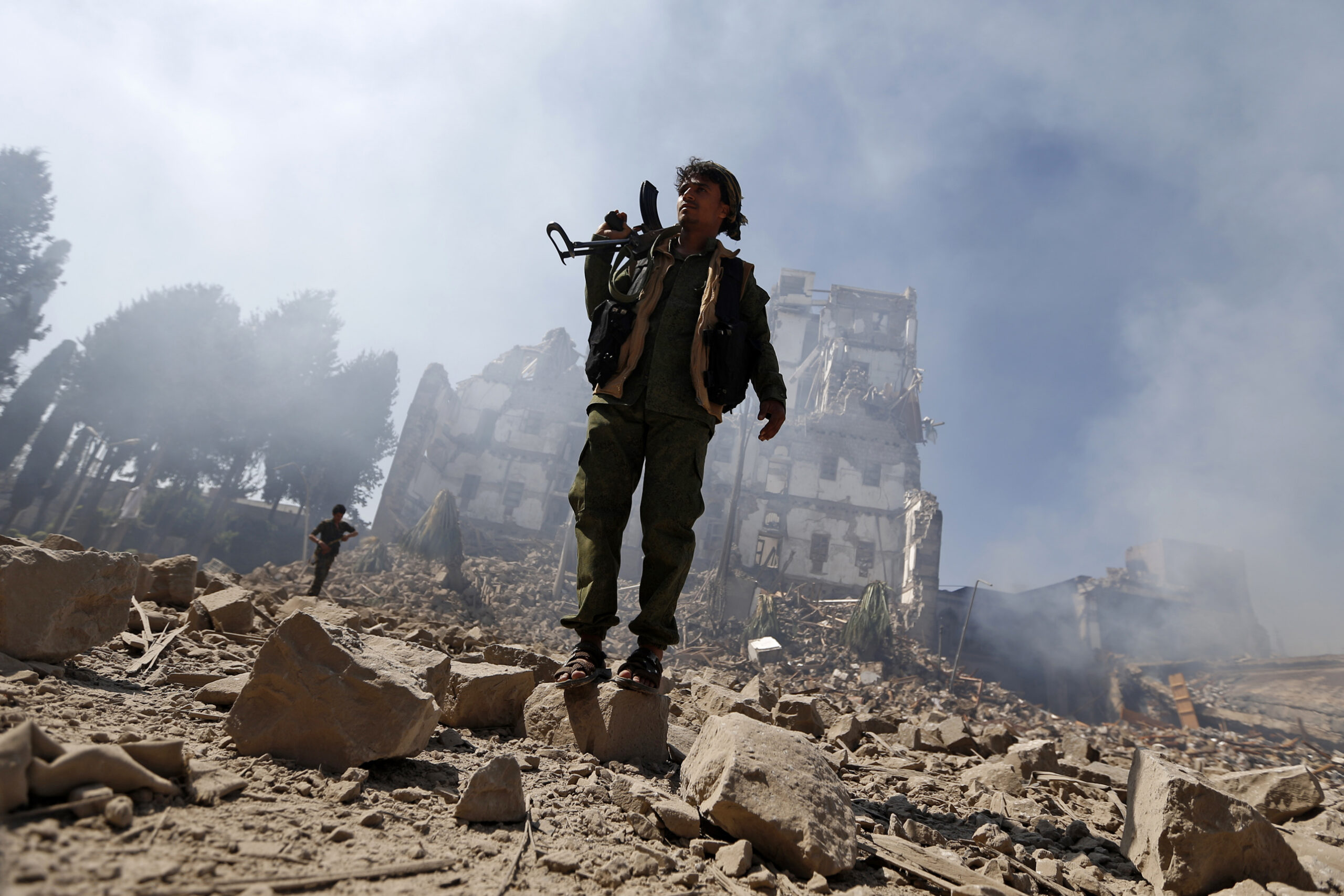Houthi rebel fighters inspect the damage after a reported air strike carried out by the Saudi-led coalition targeted the presidential palace in Sanaa on December 5, 2017.